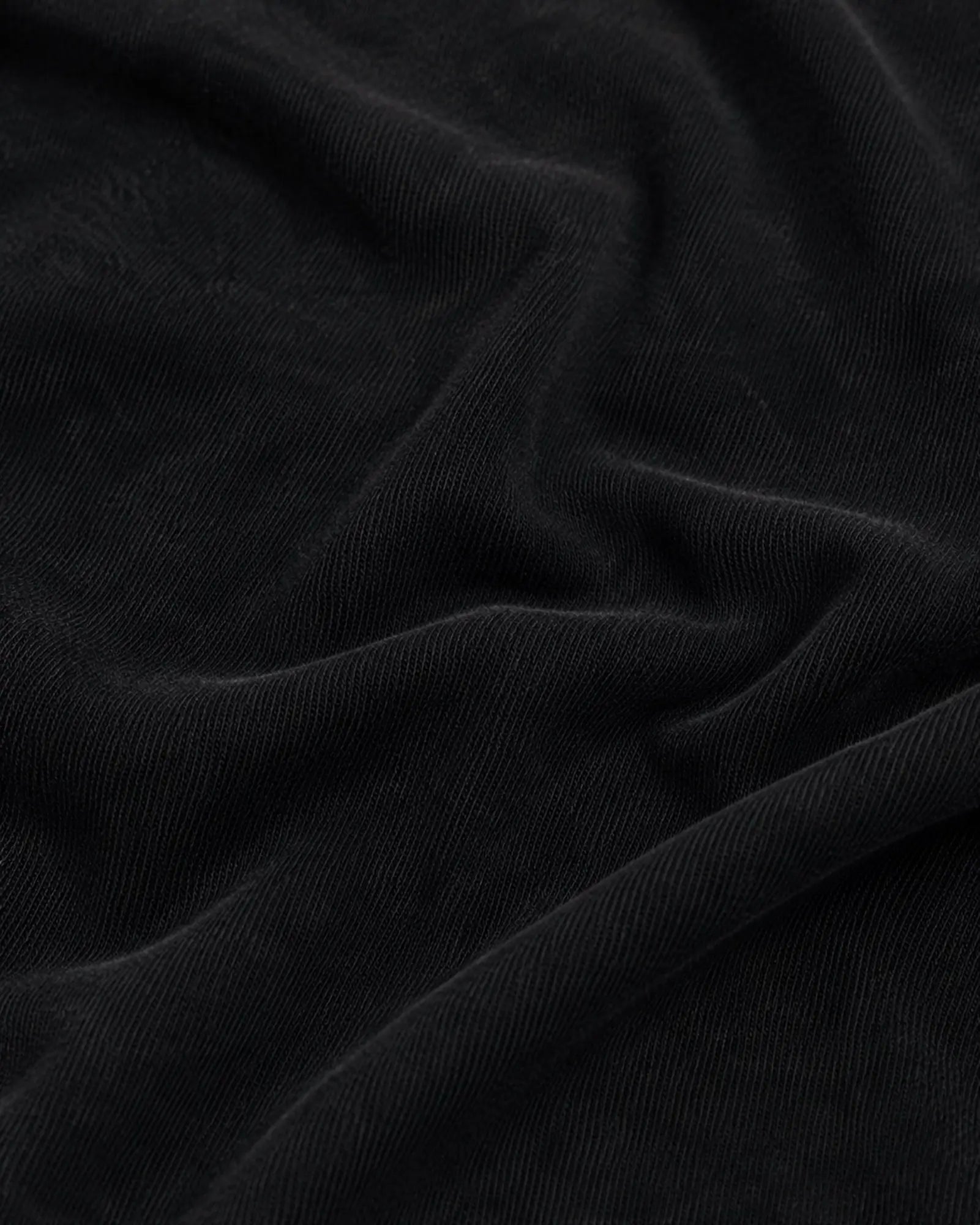 Close-up of soft, matte black fabric with visible fine-knit texture and elegant folds.