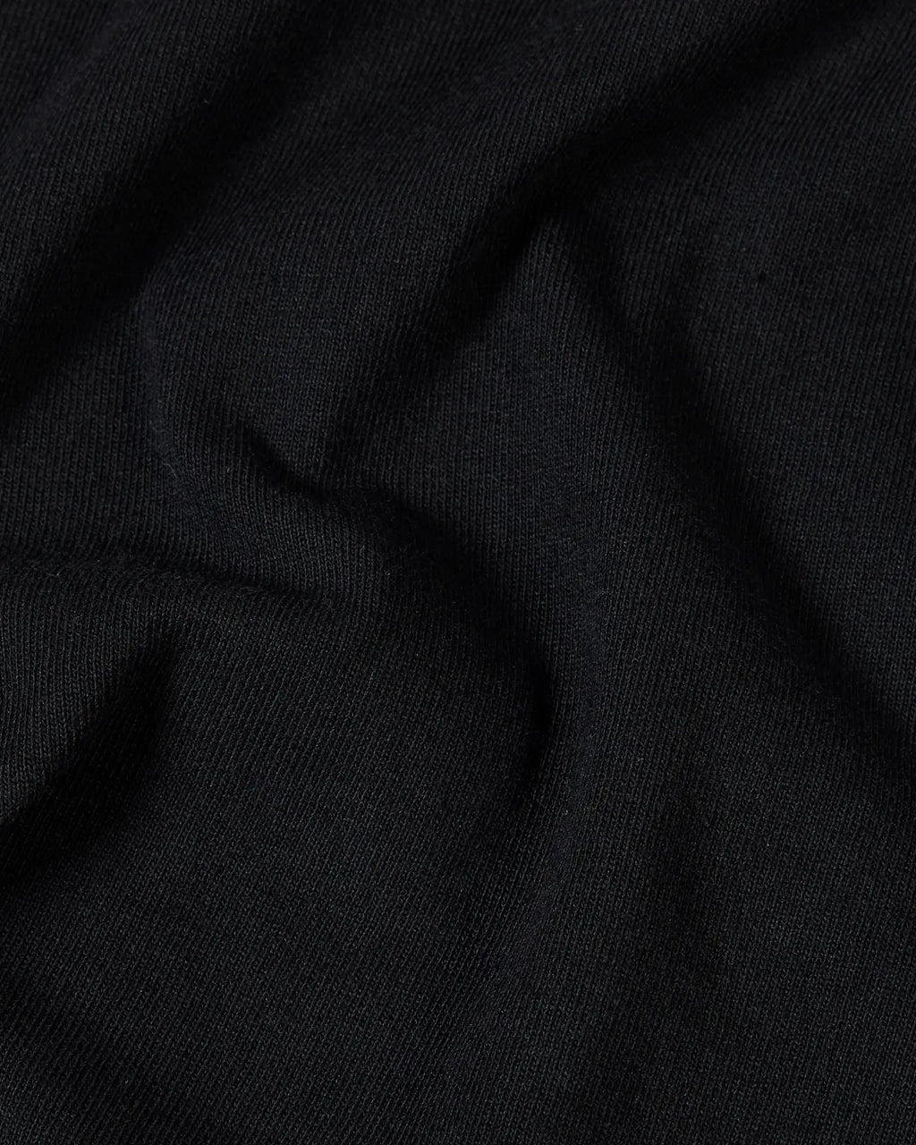 Close-up of soft, solid black cotton fabric with natural folds and a fine-knit texture.