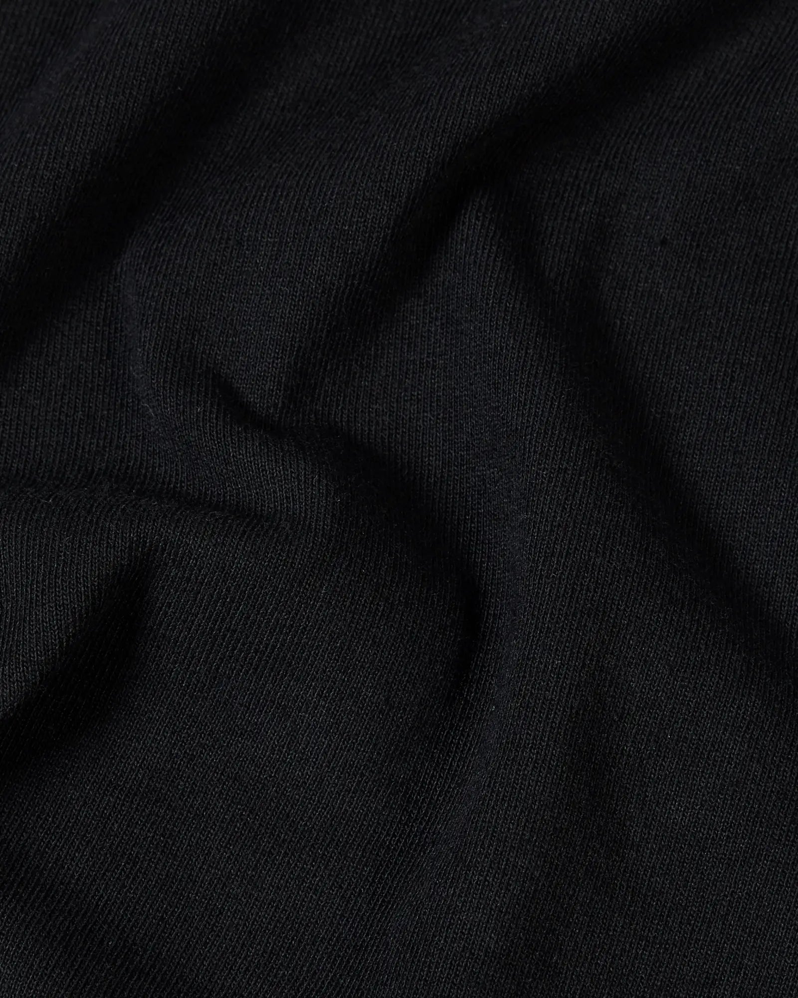 Close-up of soft, solid black cotton fabric with natural folds and a fine-knit texture.