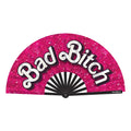 Wood Rocket bad bitch folding fan vibrant pink glitter with bold white cursive lettering and black-and-white striped interior