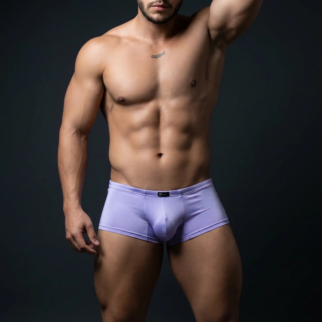Athletic male model wearing Xtremen 91219 lilac microfiber trunks in dramatic studio lighting — confident editorial pose